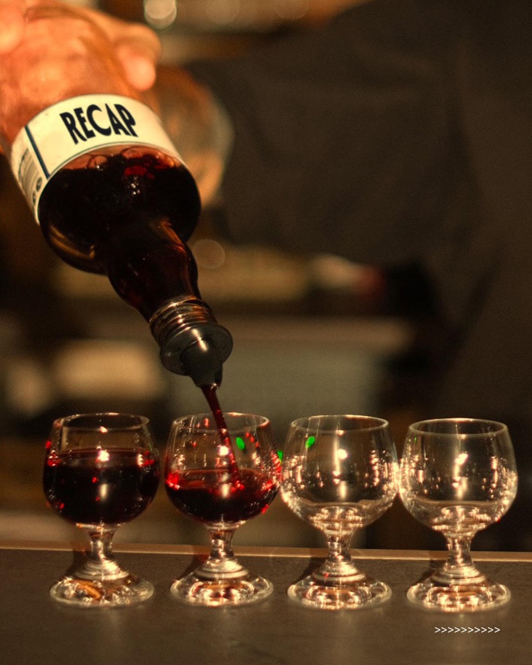 Red wine being poured into small glasses at BIBELOT bar in Riga